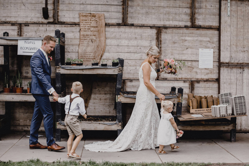 de bruid en bruidegom houden elkaars handen vast met hun twee kinderen
