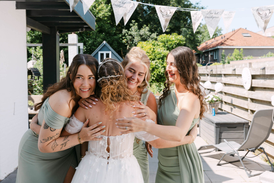 de bruid en haar bruidsmeisjes die elkaar omhelzen