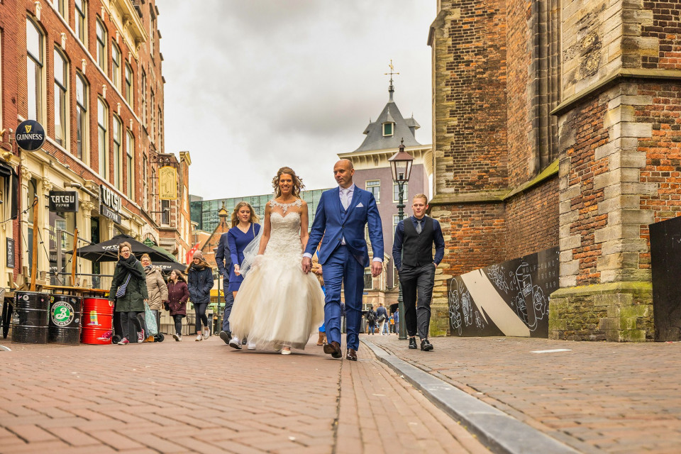 een bruid en bruidegom lopen door een straat in Amsterdam