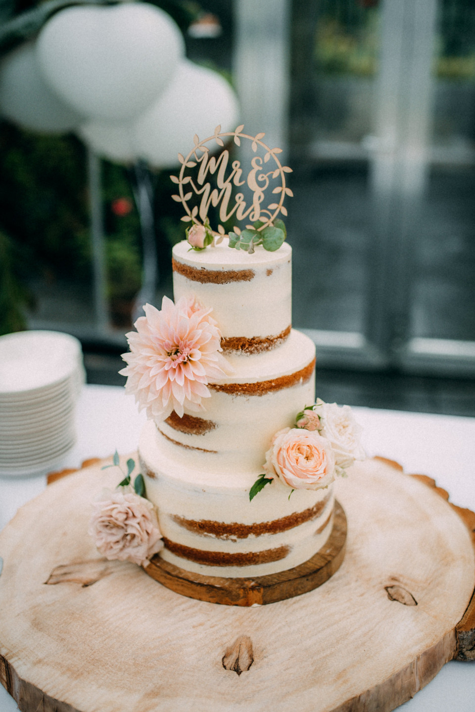 een bruidstaart op een houten plank met bloemen