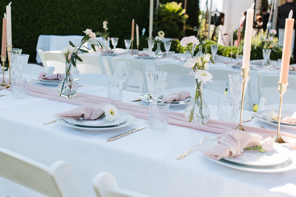 een tafel gedekt voor een formeel evenement met roze servetten en kaarsen