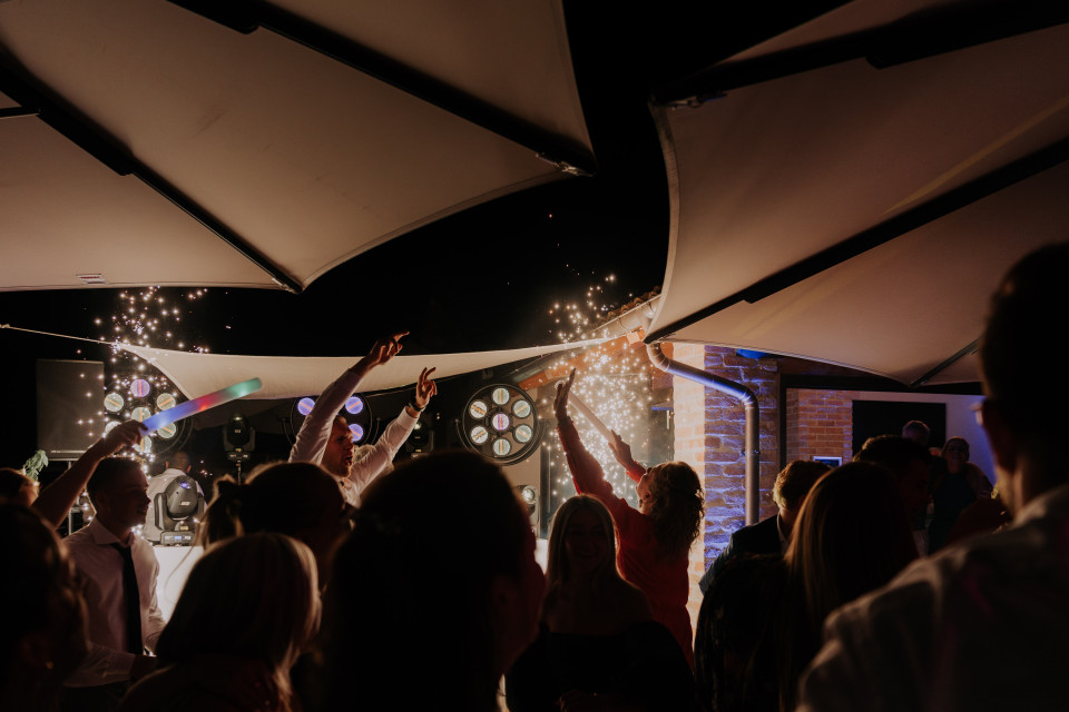 een groep mensen die onder paraplu's staan met sterretjes in de lucht op een bruiloftsreceptie in de avond