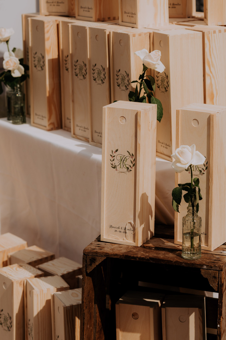 een stel houten kisten met witte rozen erin op een tafel met een wit tafelkleed