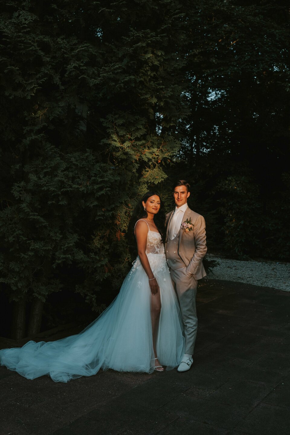 een bruid en bruidegom die poseren voor een foto voor een paar bomen