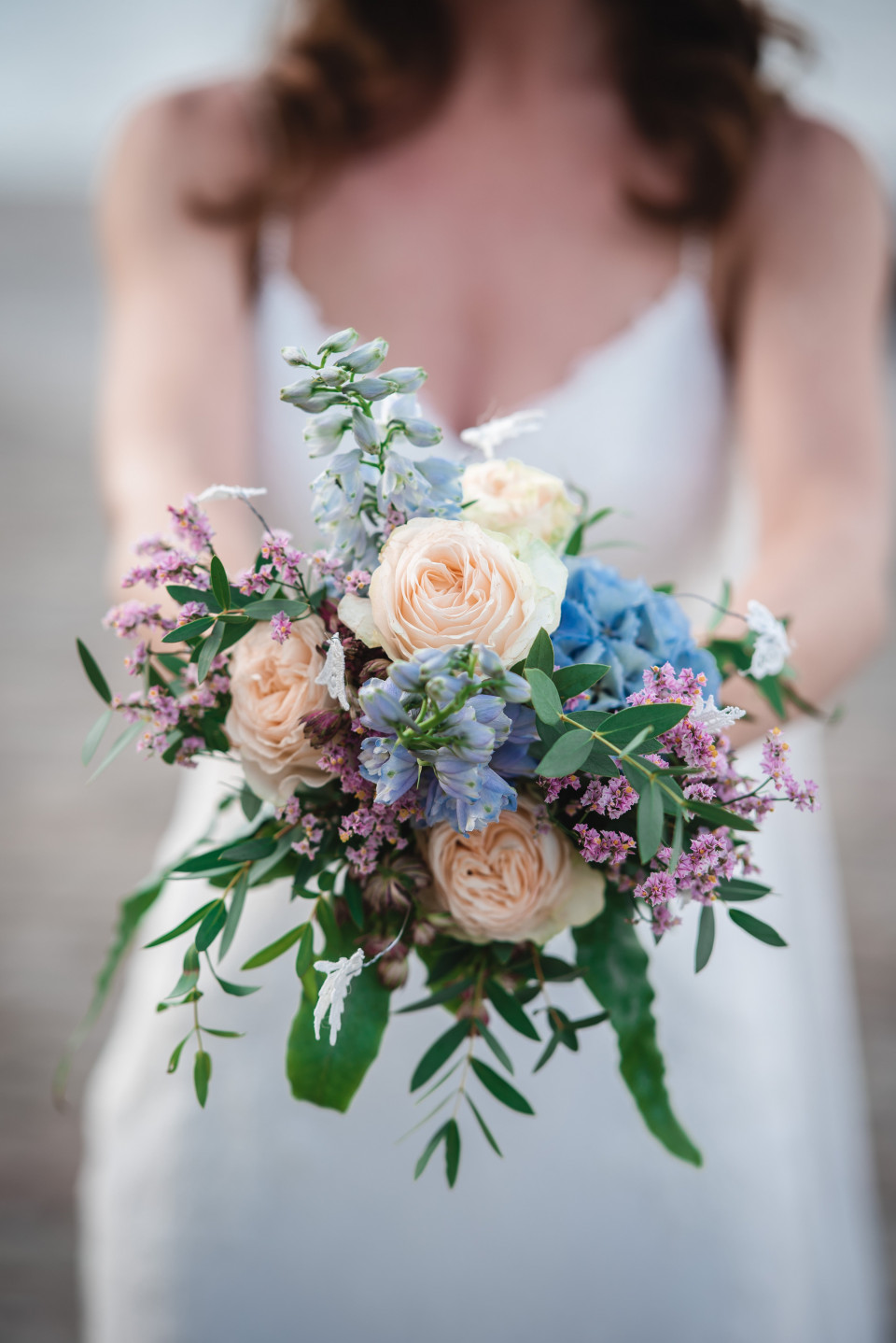 een bruid die een boeket bloemen vasthoudt op het strand