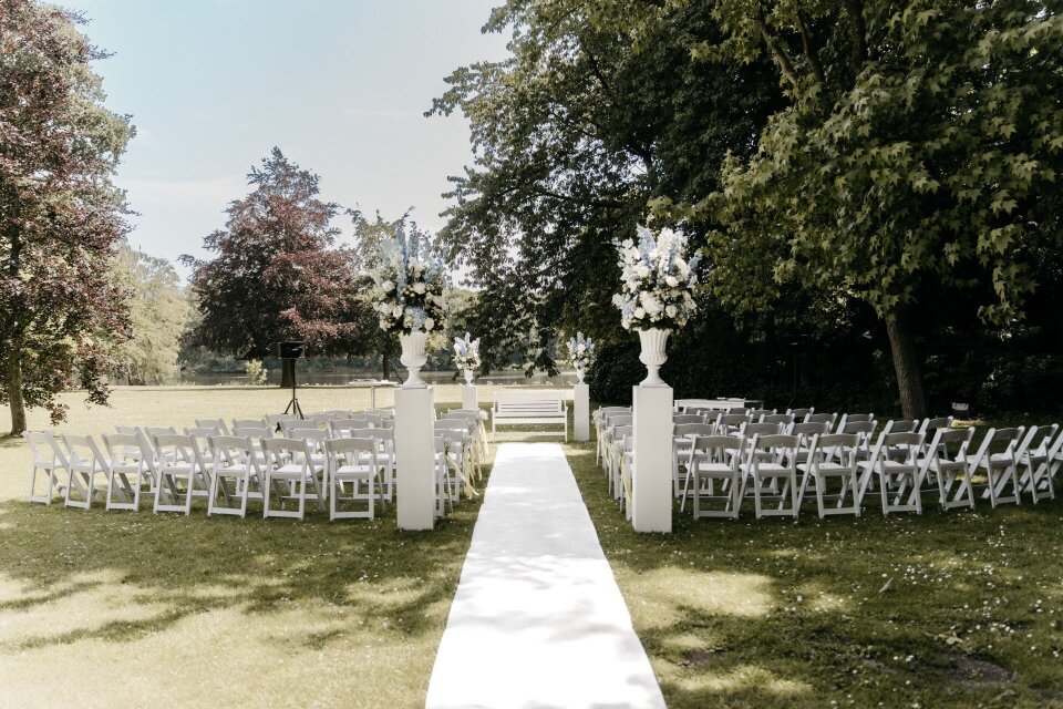 een rij witte stoelen opgesteld voor een trouwceremonie