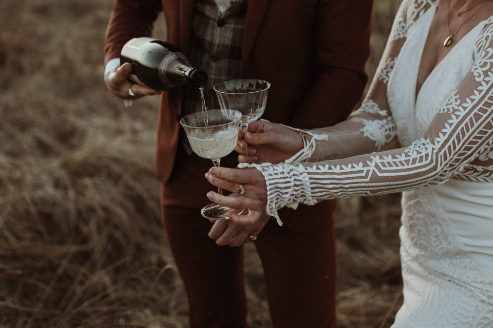 trouwkoppel proostend met champagne in het veld