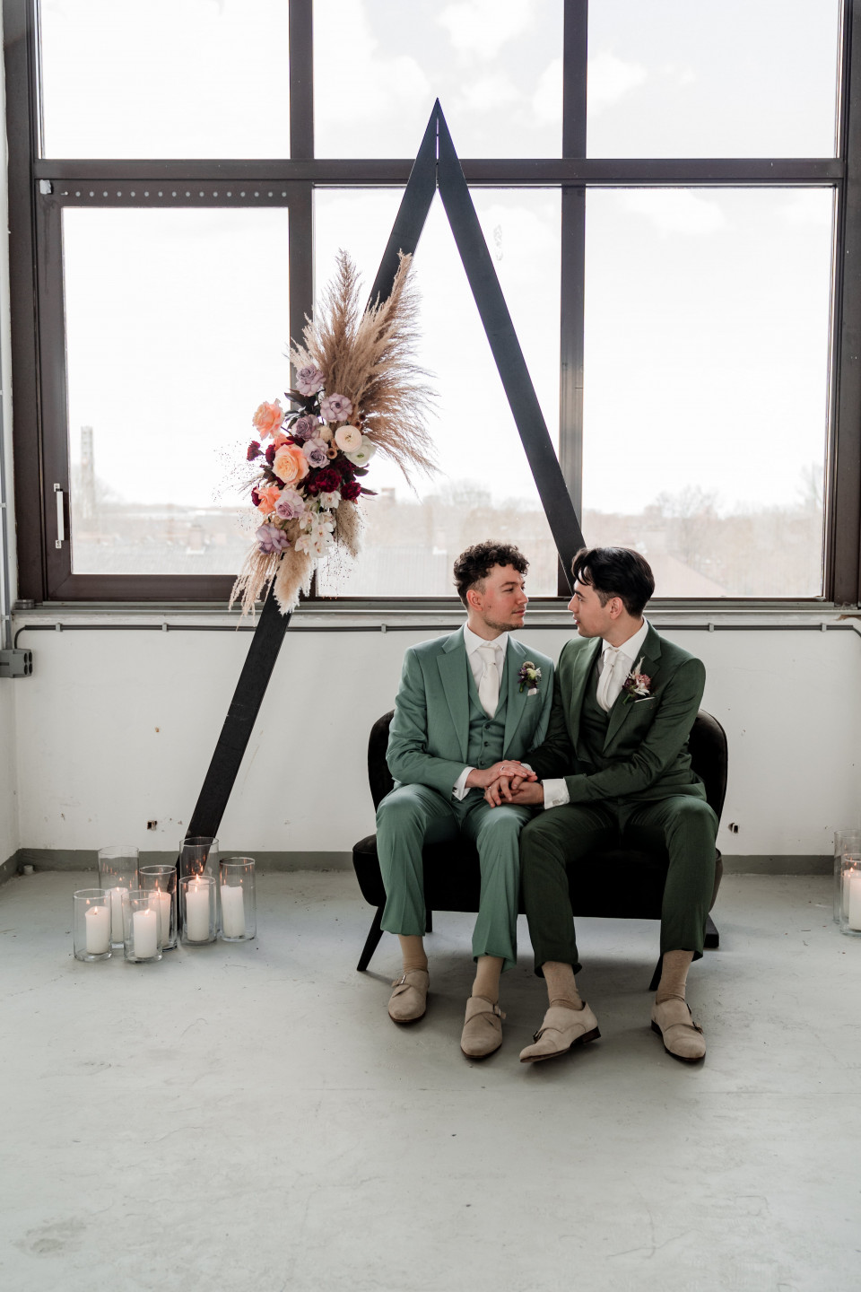 twee mannen in pakken die op een bank voor een groot raam zitten