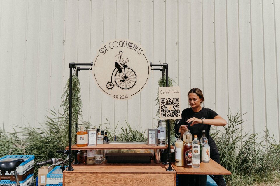 een vrouw die aan een tafel zit met flessen alcohol