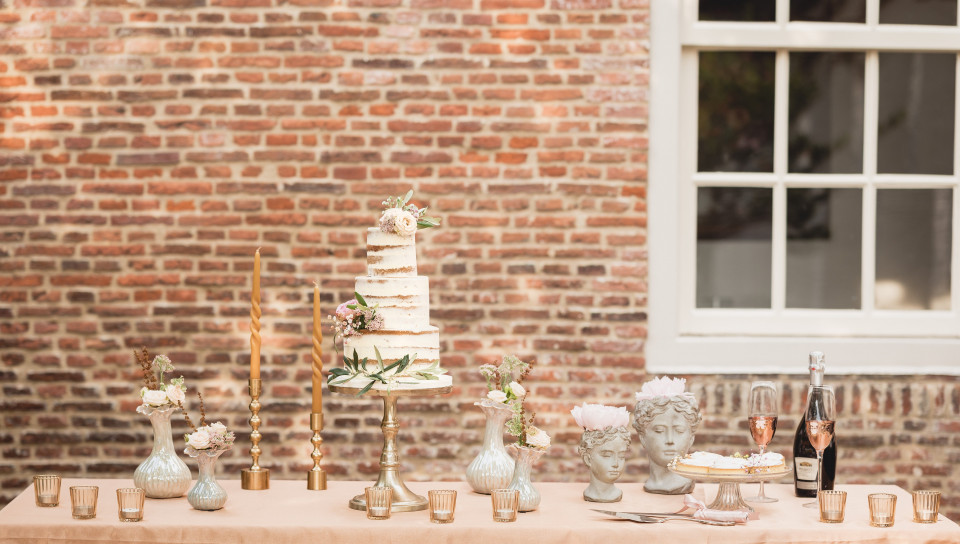 een trouwtaart op een tafel voor een bakstenen muur