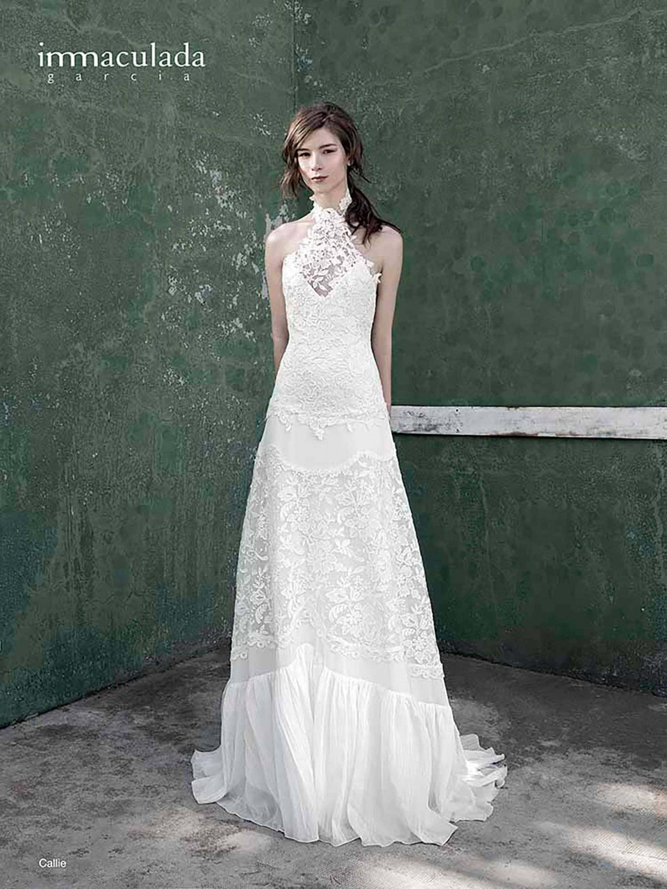 een vrouw in een witte trouwjurk die voor een muur staat