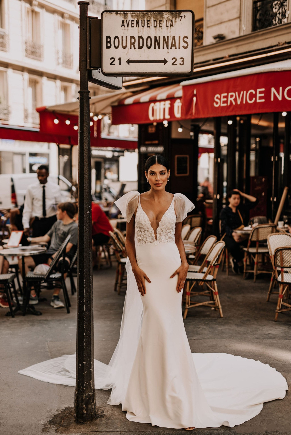 een bruid in een trouwjurk staat voor een straatnaambord