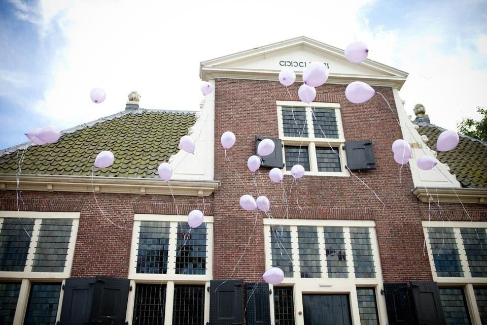 een groot bakstenen gebouw met paarse ballonnen in de lucht