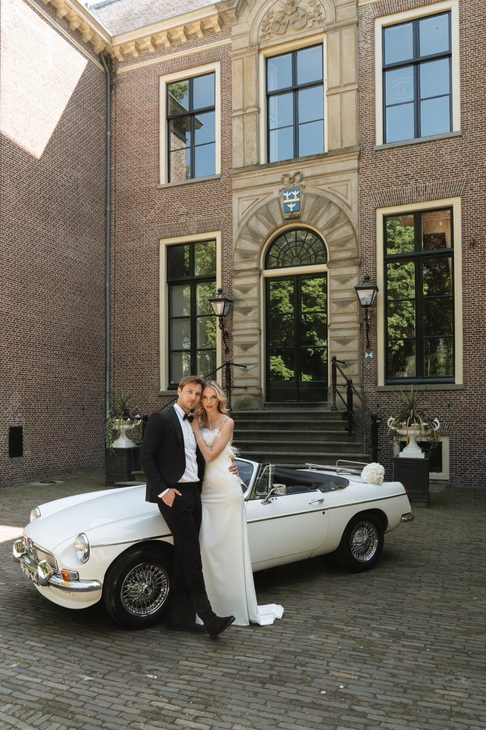 een bruid en een bruidegom staan voor een klassieke auto