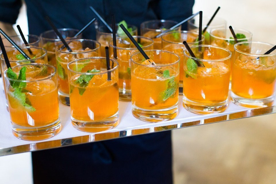 een ober die een dienblad met oranje drankjes vasthoudt