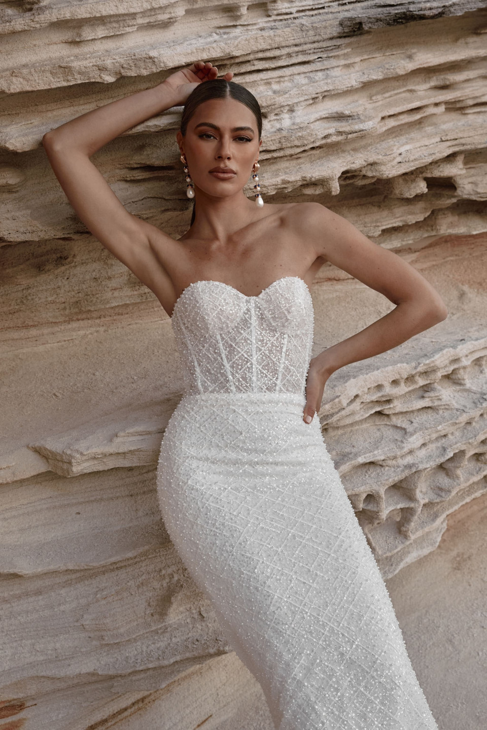 het model draagt een strapless trouwjurk met een kanten lijfje en een sweetheart halslijn