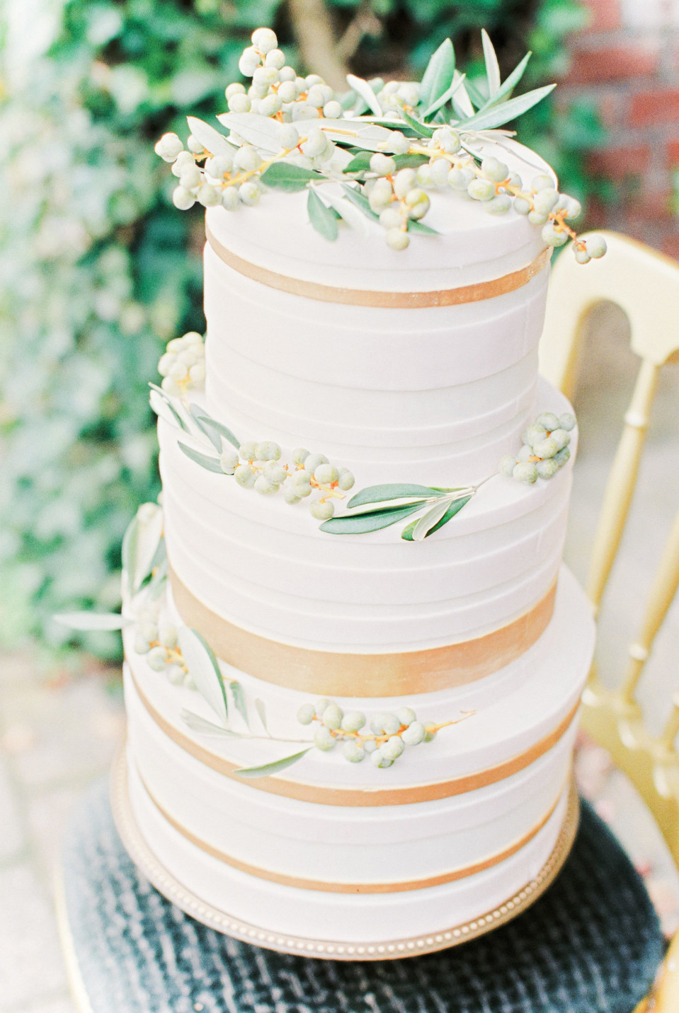 een witte bruidstaart met gouden en groene bladeren