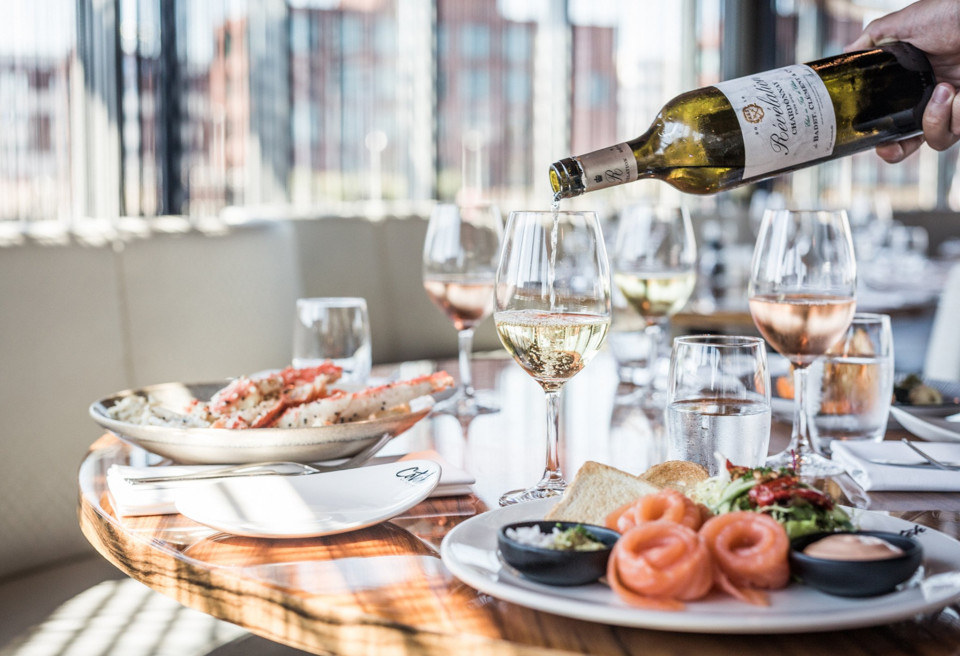 een persoon schenkt wijn in een glas in een restaurant