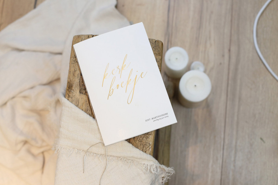 een boek met gouden belettering op een houten tafel