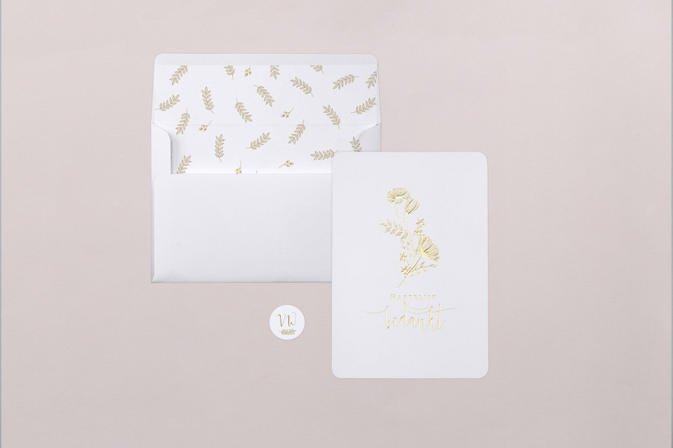 een witte envelop met gouden folie erop