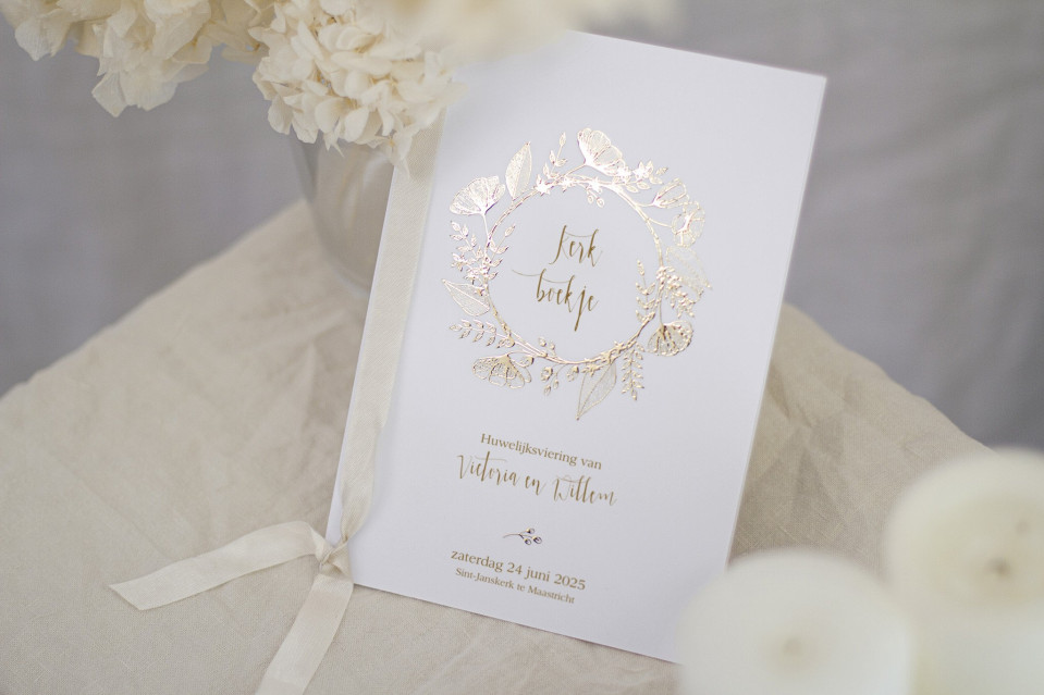 een wit trouwboek met een gouden folie design