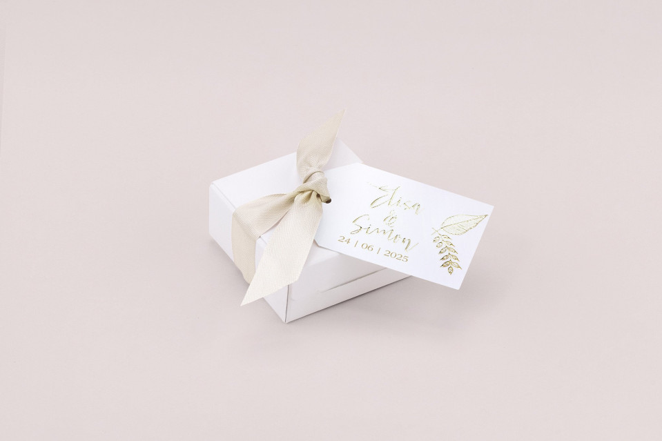 een witte cadeaubox met een gouden lint en een label
