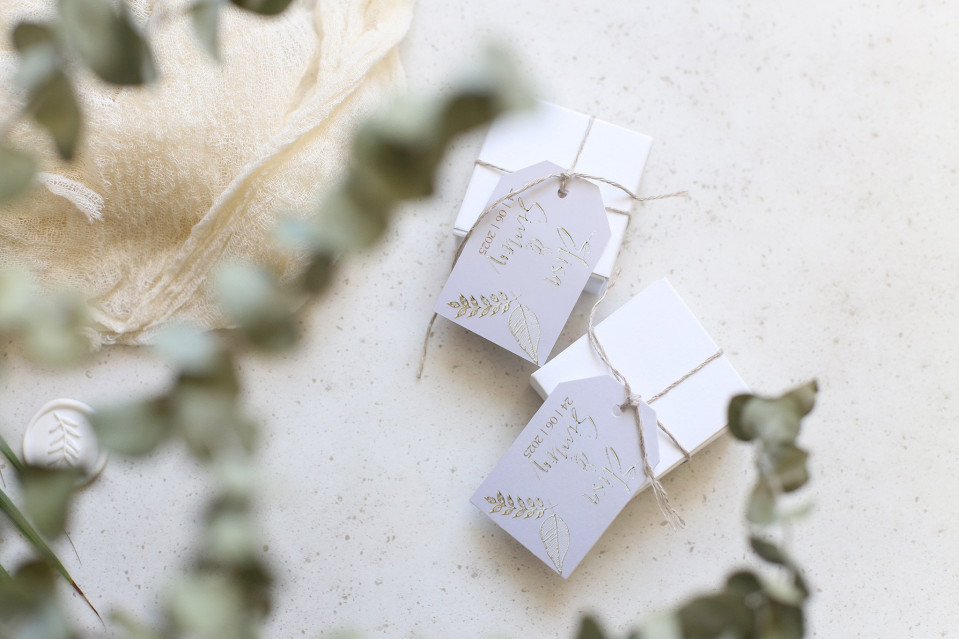 twee kleine witte cadeaulabels met gouden tekst erop