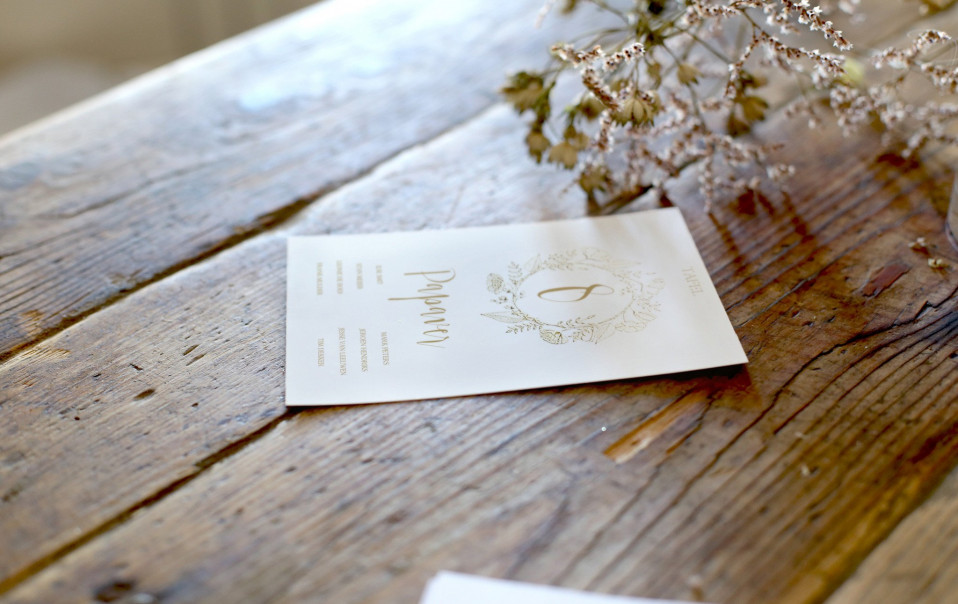 trouwuitnodiging op houten tafel met bloemen