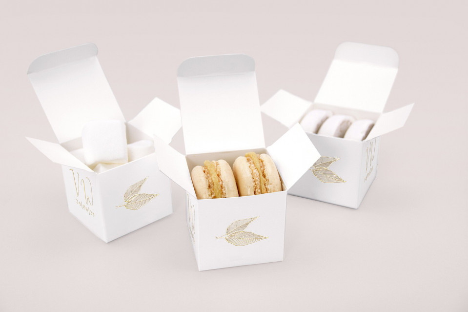 drie witte dozen met macarons en een gouden blad