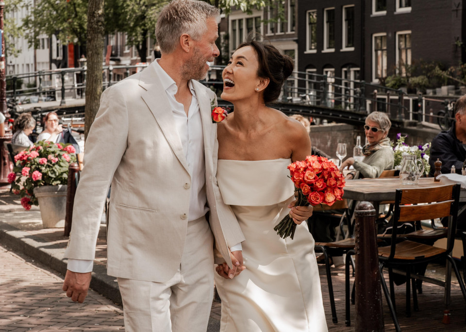 een bruid en bruidegom lopen door een straat in Amsterdam