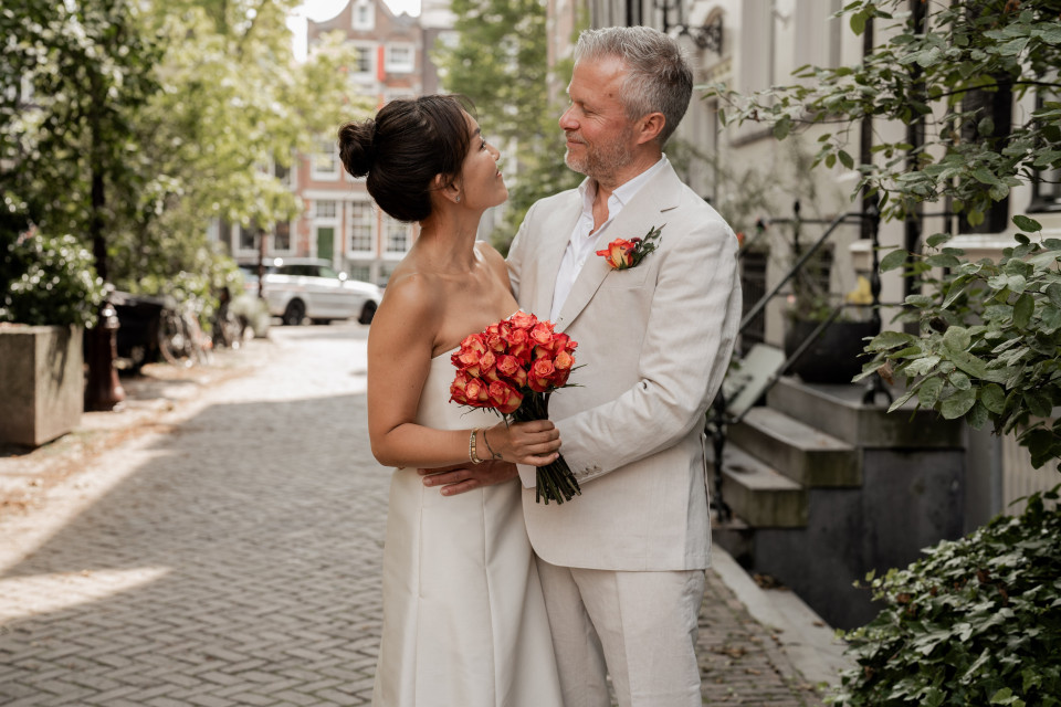 een bruid en bruidegom staan in het midden van een straat met kinderkopjes