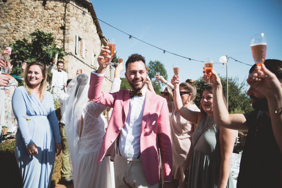 een man in een roze pak en stropdas die een glas champagne vasthoudt