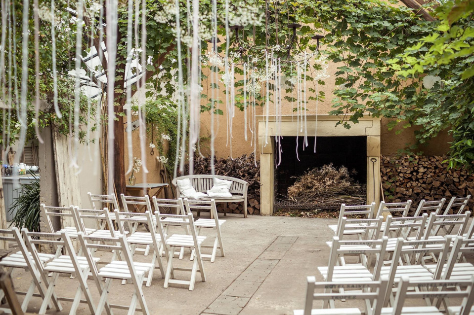 een buiten ceremoniegebied met witte stoelen en hangende witte touwen