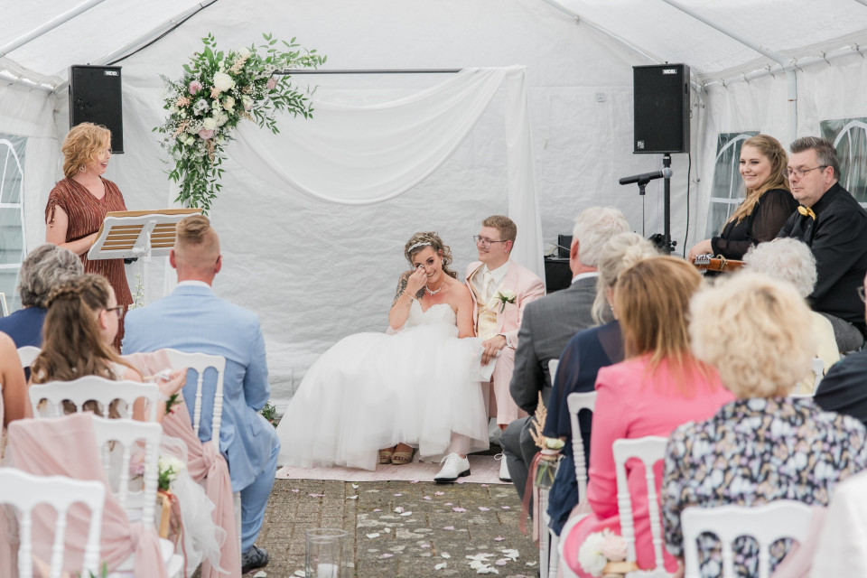 een bruiloftsceremonie in een tent met mensen die op stoelen zitten
