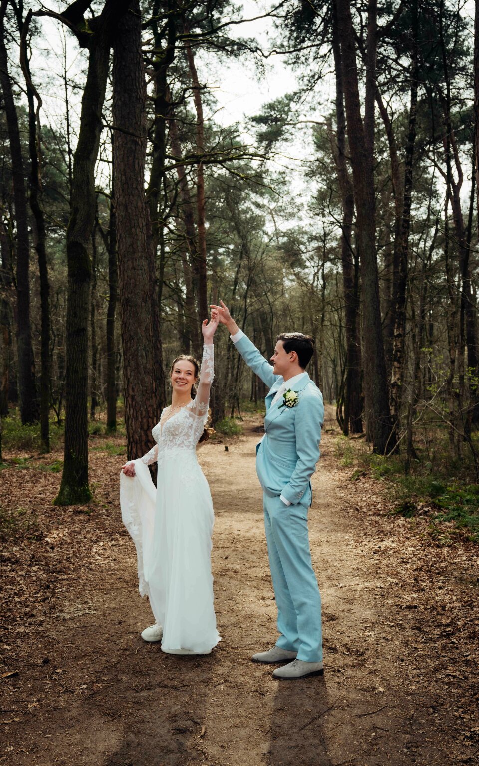 een bruid en bruidegom in het bos die elkaar een high five geven