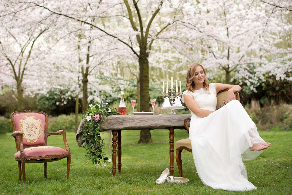 een bruid zittend op een stoel voor een tafel met kersenbloesems