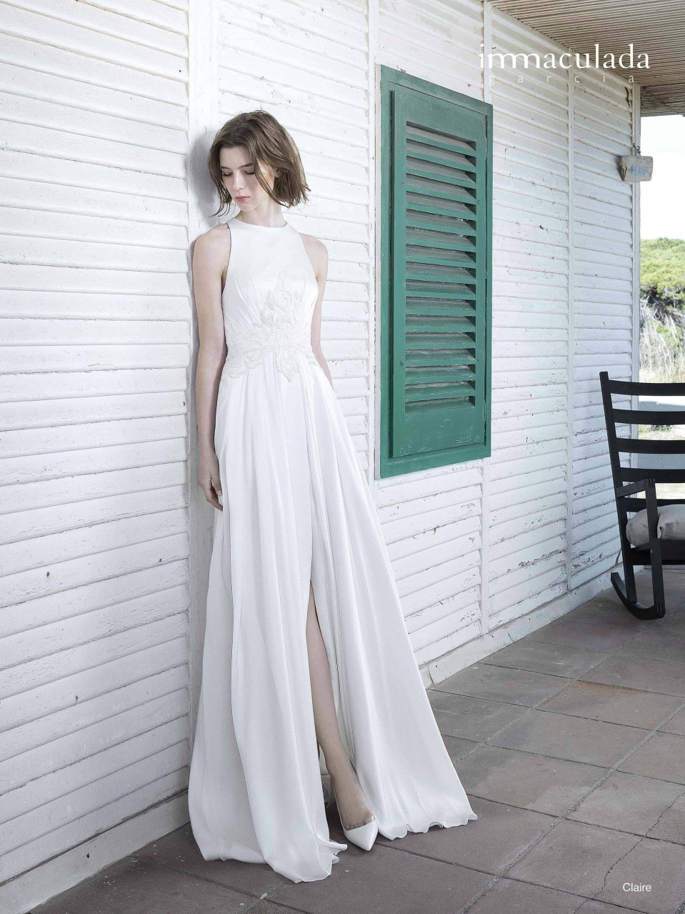 een vrouw in een witte trouwjurk die tegen een muur leunt