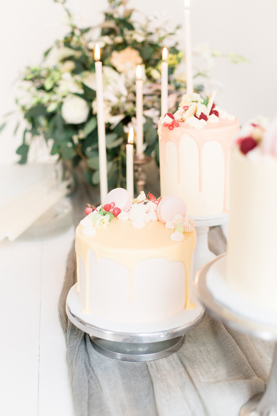 drie taarten met kaarsen bovenop een tafel