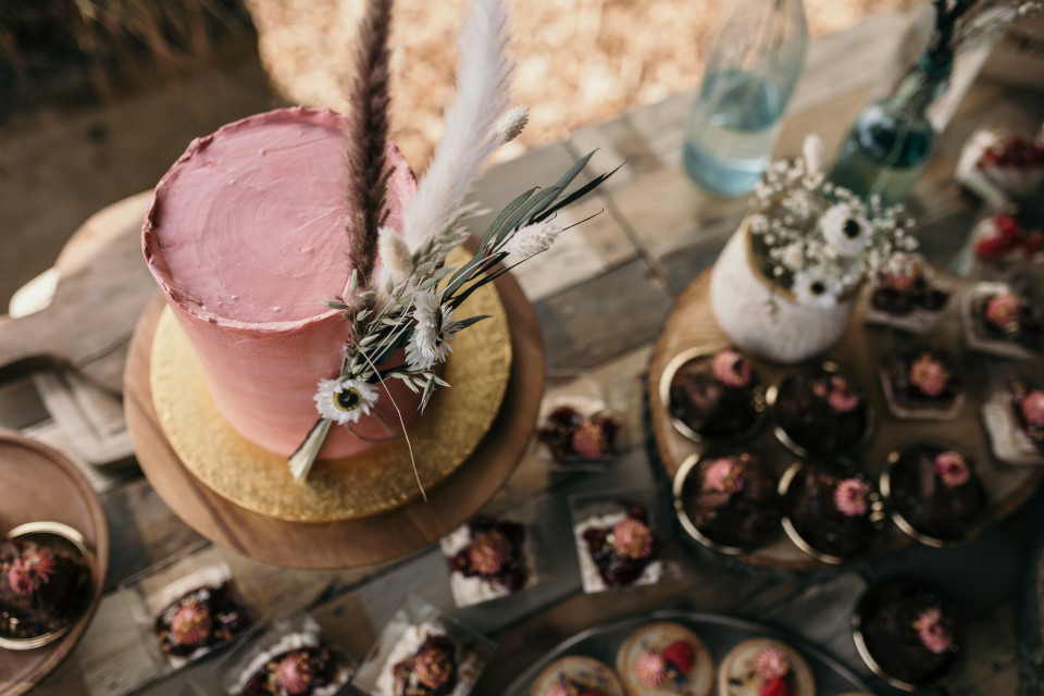 een tafel vol desserts met een roze taart erop
