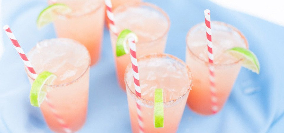 een groep van vier drankjes met rietjes en limoenschijfjes