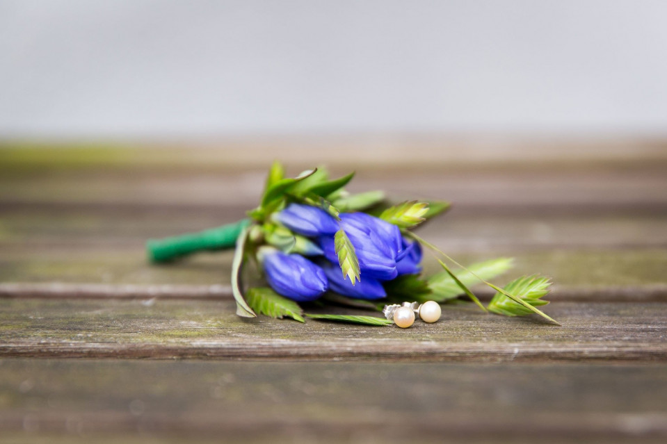 een blauwe bloem en een groene strik op een houten tafel
