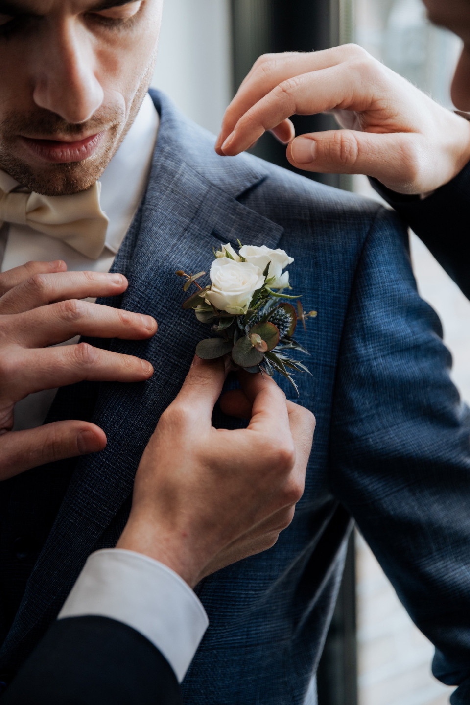 een man in een pak die een corsage aanpast