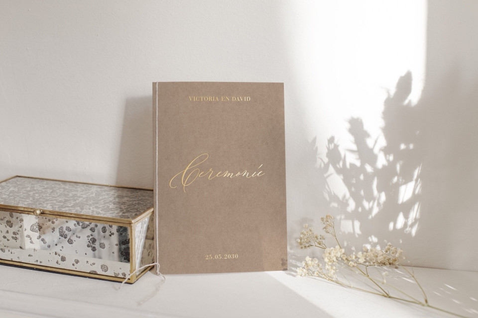 een boek dat op een tafel naast een vaas ligt