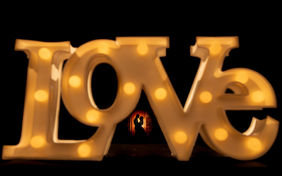 een groot verlicht liefdesbord met een man en vrouw op de achtergrond