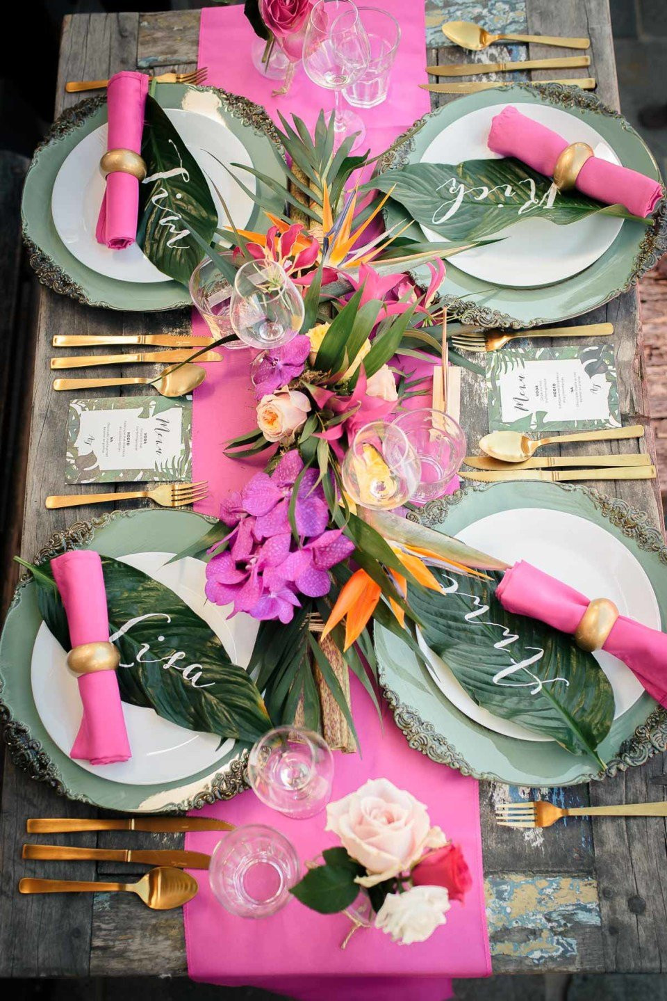 een tafelsetting met roze en gouden servetten en bloemen
