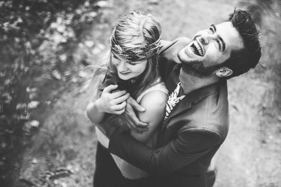 een man en vrouw lachen samen in het bos