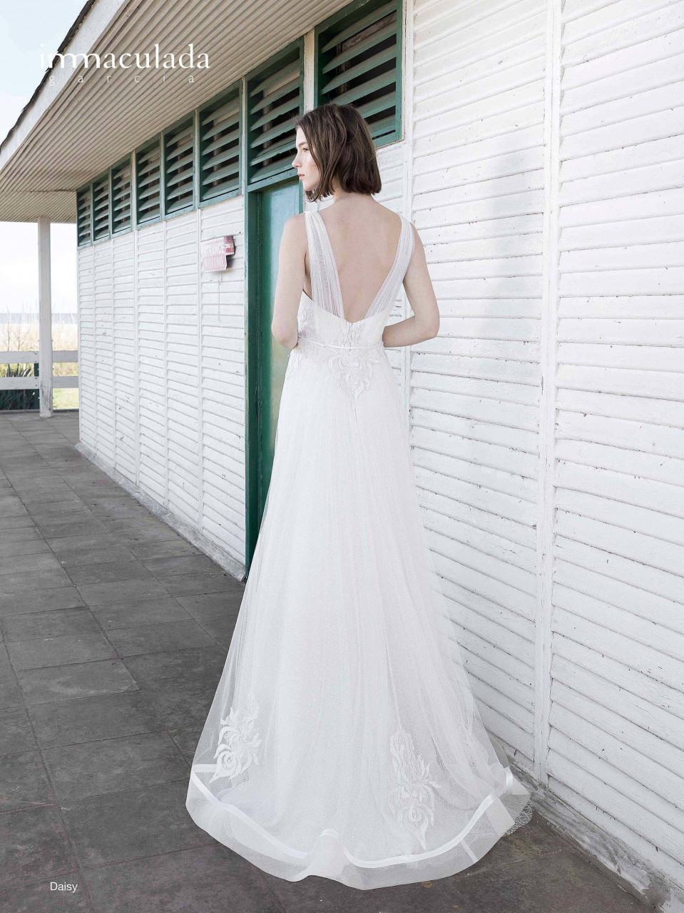 een vrouw in een trouwjurk die bij een muur staat