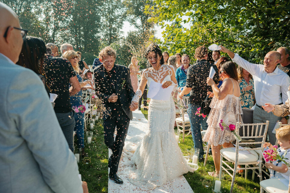 een pasgetrouwd stel loopt door het gangpad met confetti