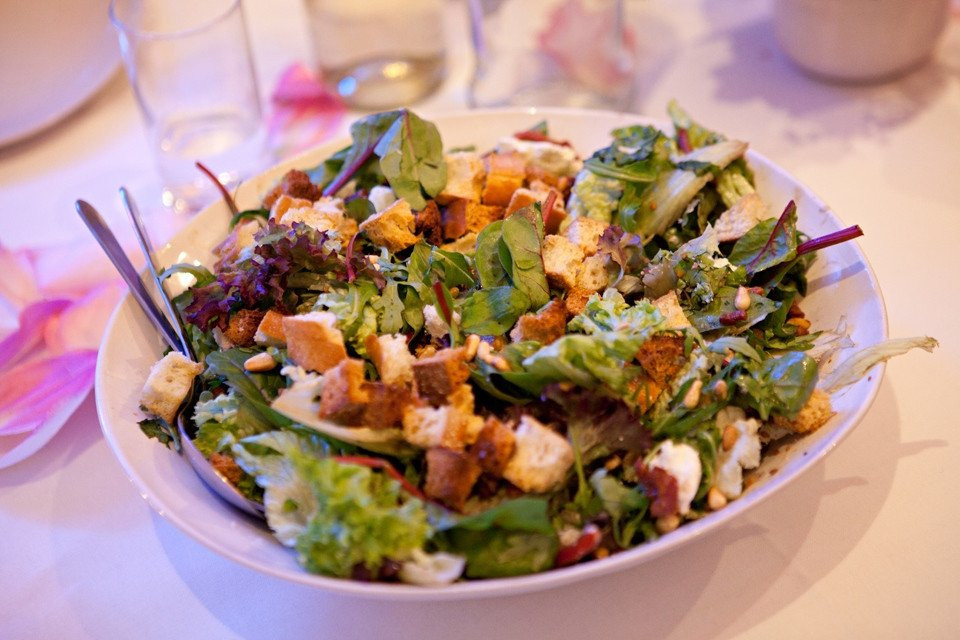 een wit bord met een salade erop