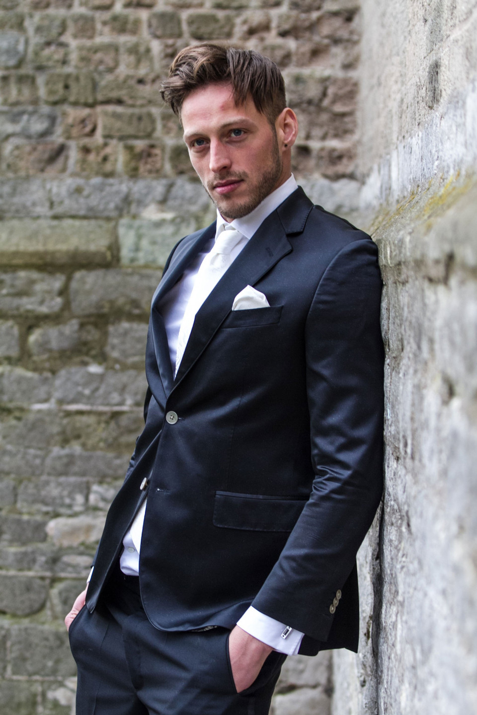 een man in een pak leunend tegen een muur